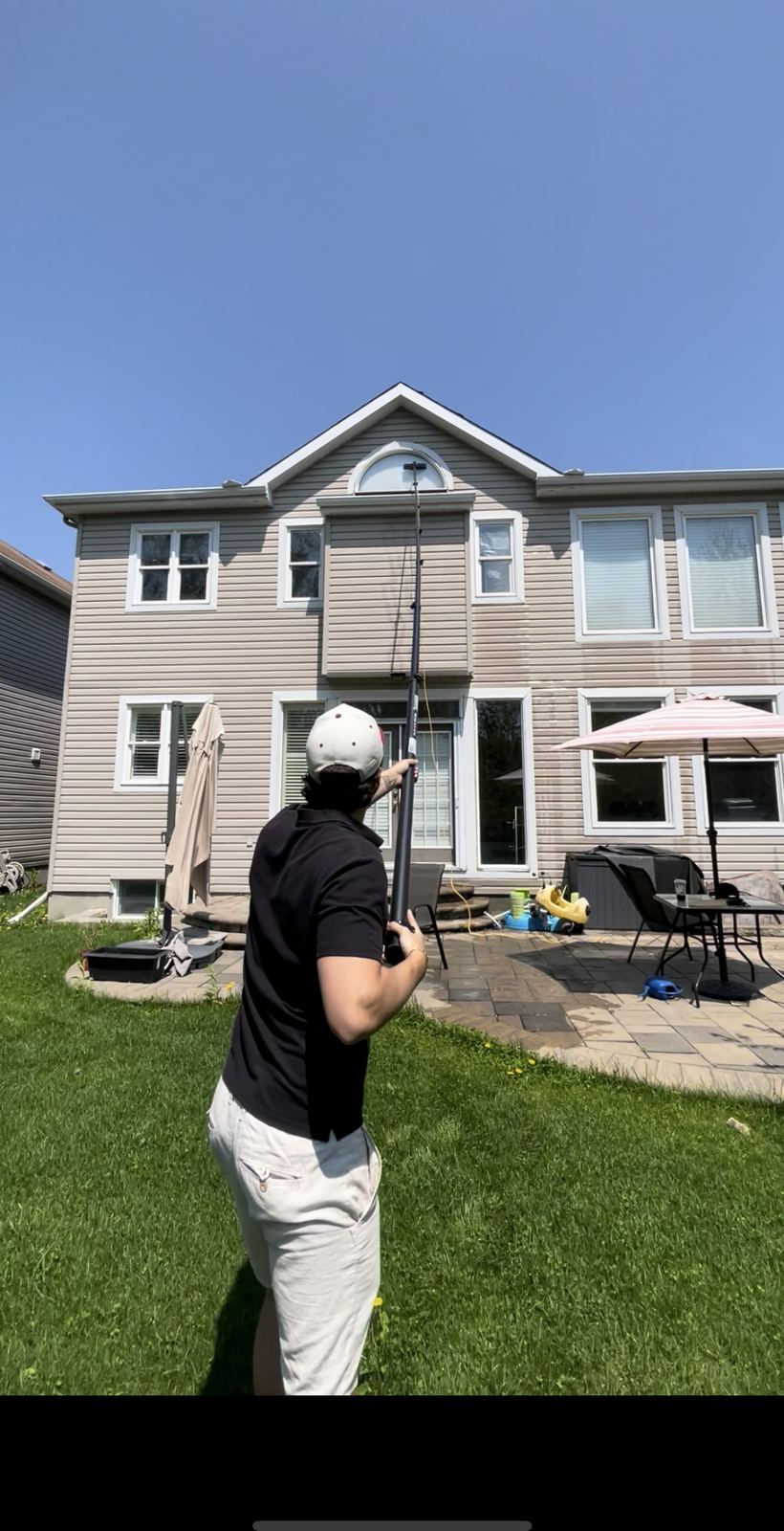 Crew member using a water-fed pole to reach a second-storey window